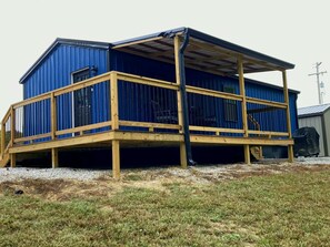 Een gebouw met twee verdiepingen, een houten terras en een metalen dak.