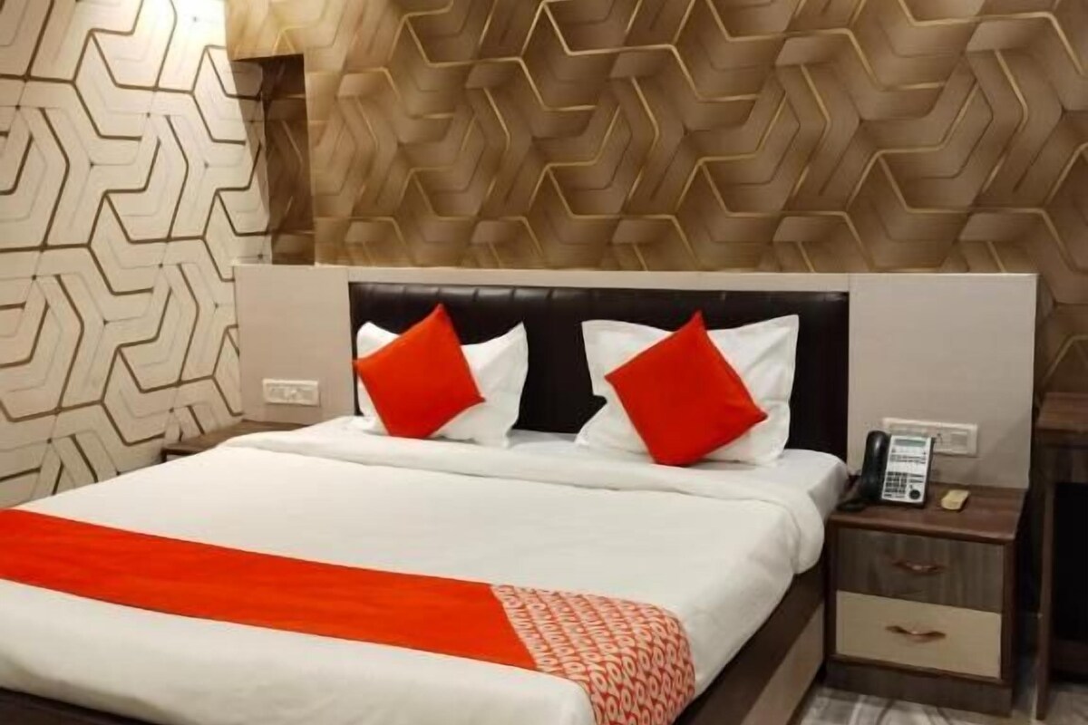 A modern bedroom with a large bed, a nightstand with a phone, and a patterned wall.