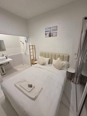 A hotel room with a bed, a bedside table, a mirror, and a shower area. - Treat Boutique Huahin 94 (Hua Hin)