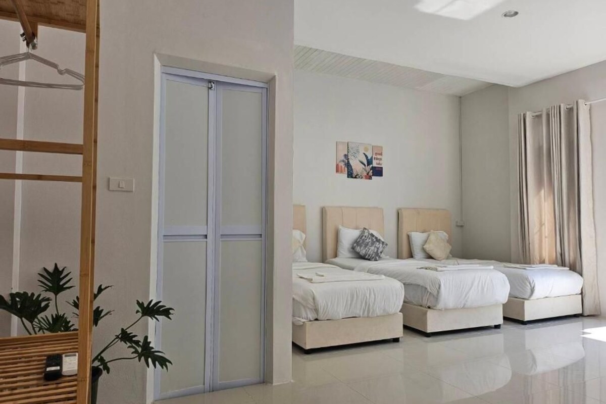 A hotel room with two beds, a wardrobe, a mirror, and a plant.