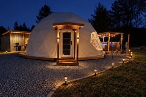 Une structure en forme de dôme géodésique, dotée d’une entrée en bois et d’un petit espace porche.