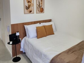Ein Hotelzimmer mit einem Bett, einem Nachttisch mit Lampe sowie zwei Wandbildern.