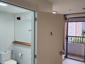 Ein Badezimmer mit Toilette, Dusche und einer Glastür, die auf einen Balkon führt.