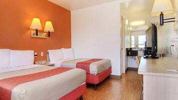 Habitación de hotel con dos camas, un escritorio y un espejo.