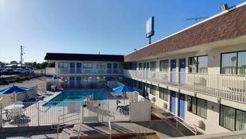 Un motel con piscina, mobiliario exterior y un área de terraza amurallada.