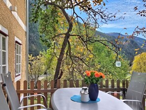 Un patio con una mesa, sillas y un jarrón de flores.