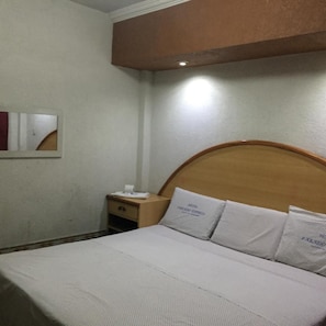A hotel room with a bed, a nightstand, a mirror, and a wall-mounted light fixture. - Hotel Paraiso Express (Veracruz)