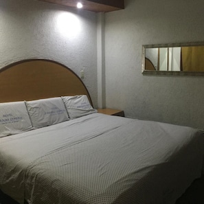 A bed with a headboard, a nightstand, and a wall-mounted mirror. - Hotel Paraiso Express (Veracruz)