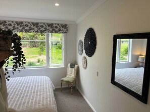 Quarto com duas camas, uma cadeira, um espelho grande e detalhes decorativos nas paredes.