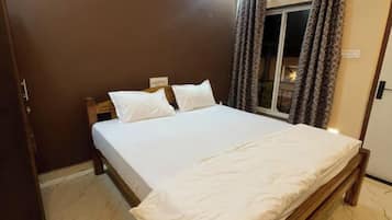 A neatly made bed with white linens in a room with a wooden headboard.