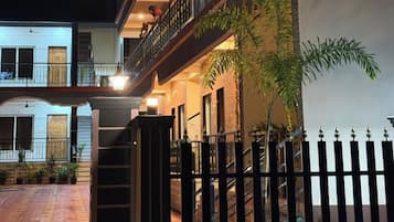 A multi-story building with balconies, a gated entrance, and a staircase leading to the upper floors.