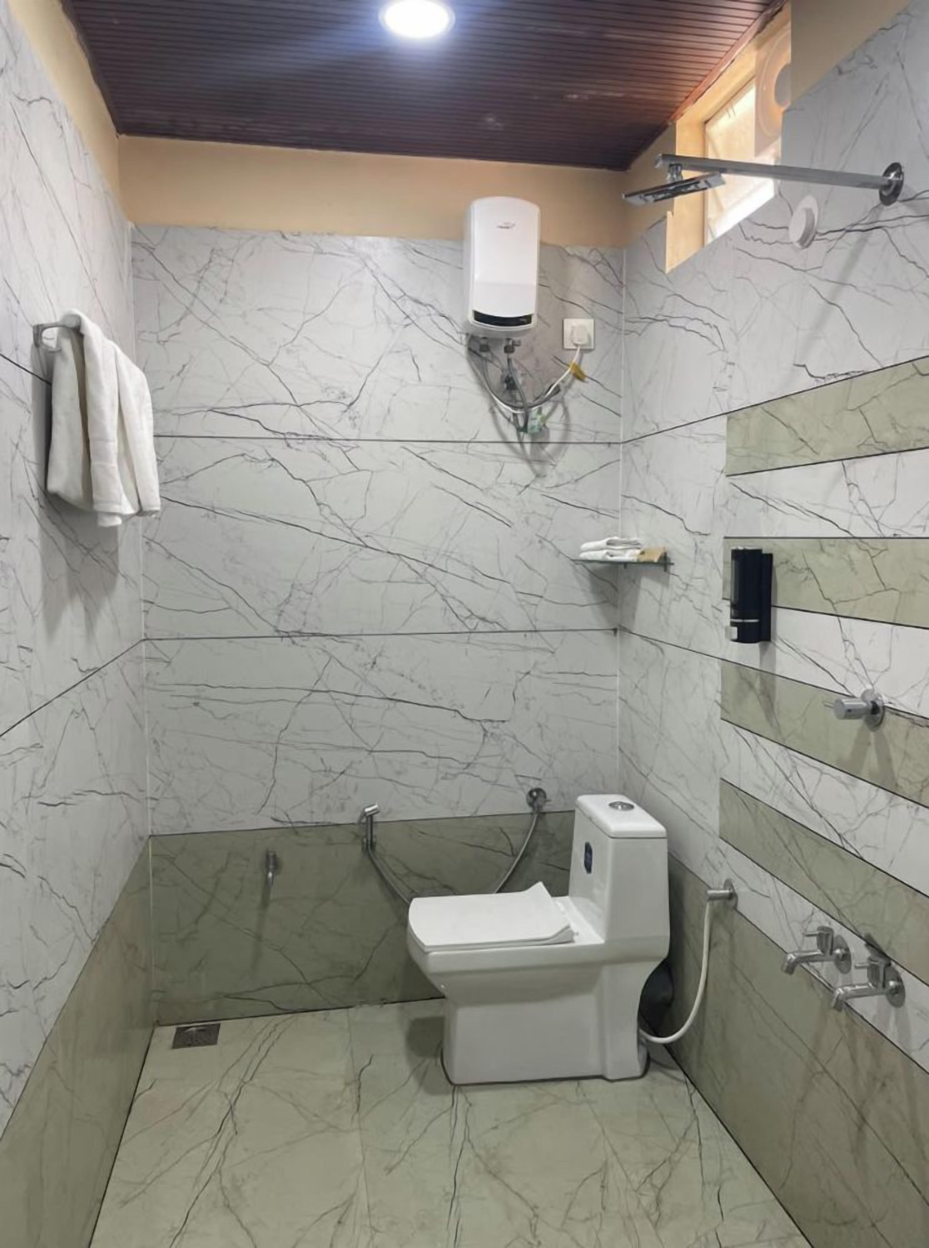 A bathroom with a toilet, a shower, and a hand dryer.