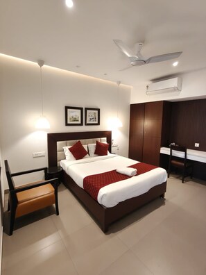 A modern hotel room with a large bed, bedside tables, a desk, and a chair. - Arabian Pearl By Foxin Room (Kochi)