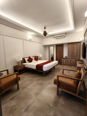 A modern hotel room with a large bed, a desk, a chair, and a TV. - Arabian Pearl By Foxin Room (Kochi)