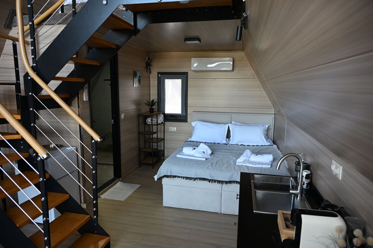 Una camera da letto moderna con una scala in legno, un letto con lenzuola bianche, un comodino e un armadio a muro.