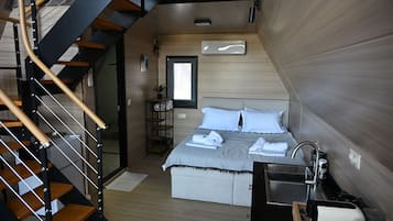 Una camera da letto moderna con una scala in legno, un letto con lenzuola bianche, un comodino e un armadio a muro.