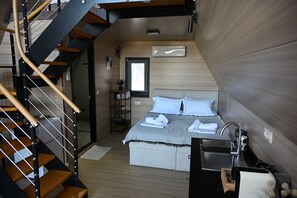 Una camera da letto moderna con una scala in legno, un letto con lenzuola bianche, un comodino e un armadio a muro.