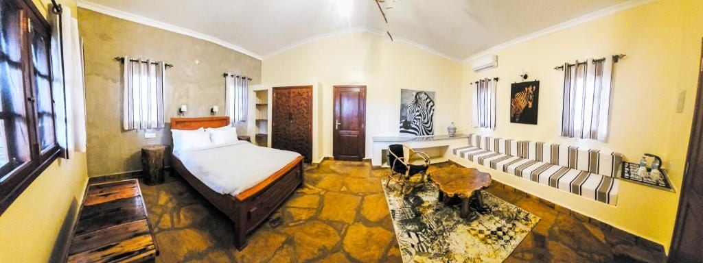 A room with a bed, a desk, a sofa, and a rug.