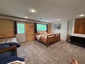 Une chambre à coucher avec un lit, un petit lit, une cheminée et une fenêtre avec des rideaux.