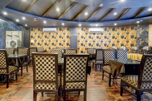 Restaurante com decoração de parede estampada, diversas mesas e cadeiras.