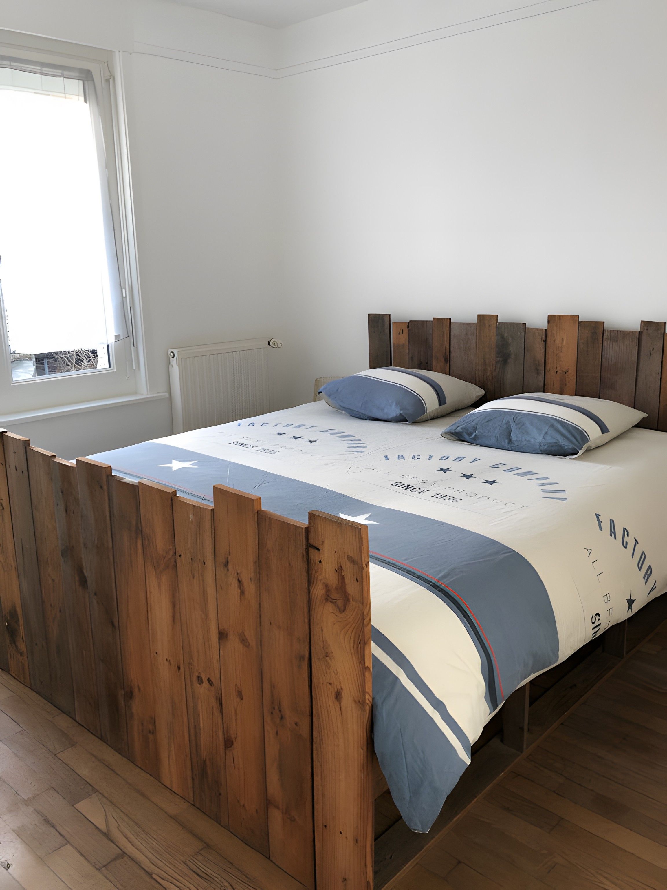 Une chambre à coucher avec un lit en bois, une fenêtre et un radiateur.