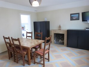 Un coin repas avec une table et des chaises en bois, une cheminée, un téléviseur et un tableau encadré au mur.