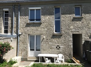 Un bâtiment en pierre doté d’un balcon, d’une table et de deux chaises.