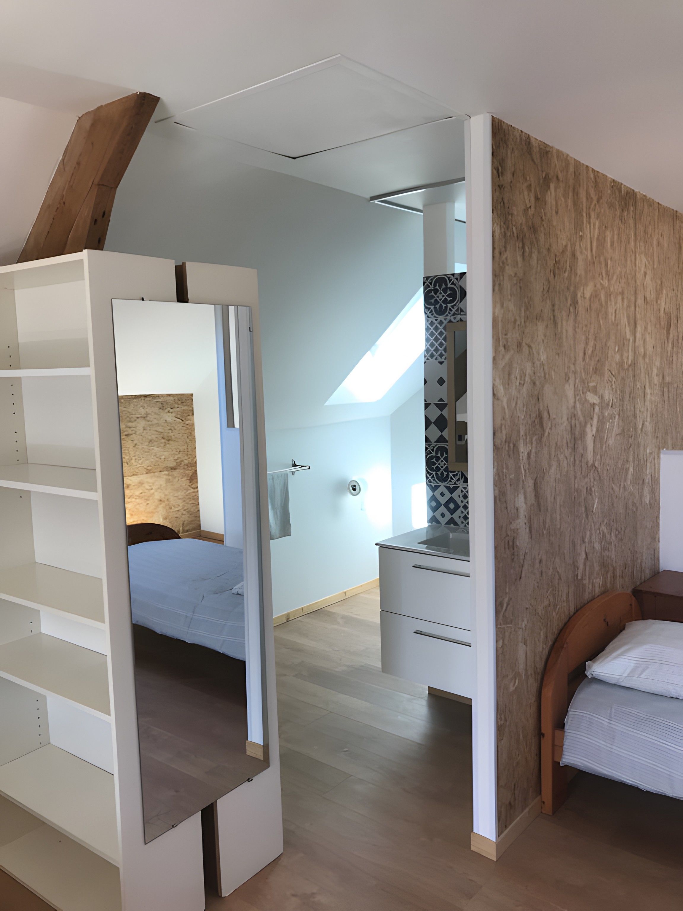 Une chambre à coucher avec un lit, une armoire et une salle de bain visible à travers une porte ouverte.
