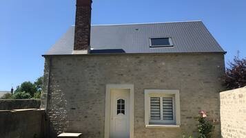 Un bâtiment à deux étages, doté d’une cheminée en briques, d’une petite fenêtre et d’une porte blanche.