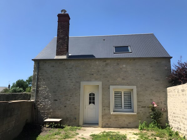 Un bâtiment à deux étages, doté d’une cheminée en briques, d’une petite fenêtre et d’une porte blanche.