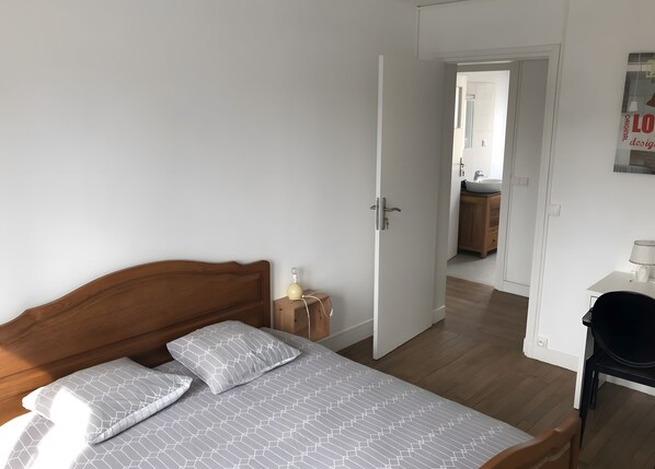 Une chambre à coucher avec un lit en bois, une table de chevet et une porte donnant sur une salle de bain.