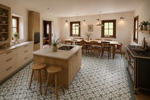A spacious kitchen with a central island, wooden cabinets, and a dining area with chairs.