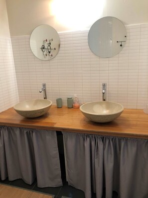 Une salle de bain avec deux lavabos, un miroir au-dessus de chacun, et un luminaire fixé au mur.