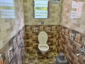 A compact bathroom with a toilet, a window, and a wall-mounted sign. - Mamachi Wadi Resort (Alibaug)