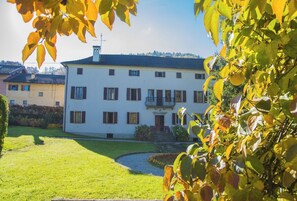 Ein weißes Gebäude mit Balkon, umgeben von einer gepflegten Rasenfläche und einem Garten.