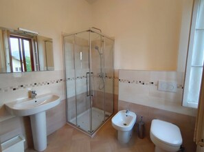 Ein Badezimmer mit Duschkabine, Standwaschbecken, Bidet und Toilette.