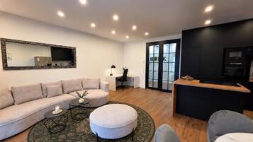 Una sala de estar moderna con sofá, reposapiés, mesa de centro y televisor.