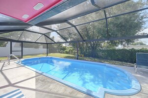 Una piscina interior con vistas despejadas del entorno, que incluyen árboles y una valla.
