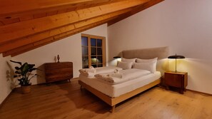 A bedroom with a wooden ceiling, a bed with white linens, a nightstand, a dresser, and a window. - New Listing (Riegsee)
