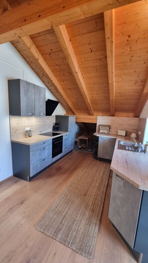 A modern kitchen with wooden beams, grey cabinets, and a wooden floor. - New Listing (Riegsee)