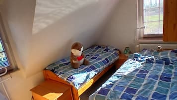 A room with two wooden beds, a small table, and a window with blinds.