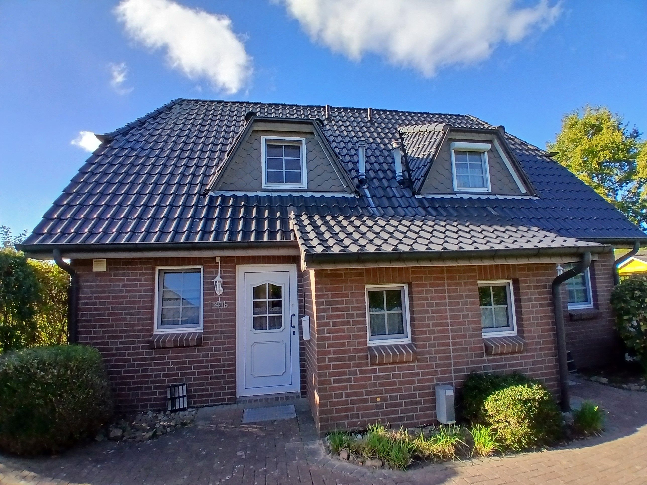 A two-story house with a tiled roof, a front door, and two windows on the ground floor.