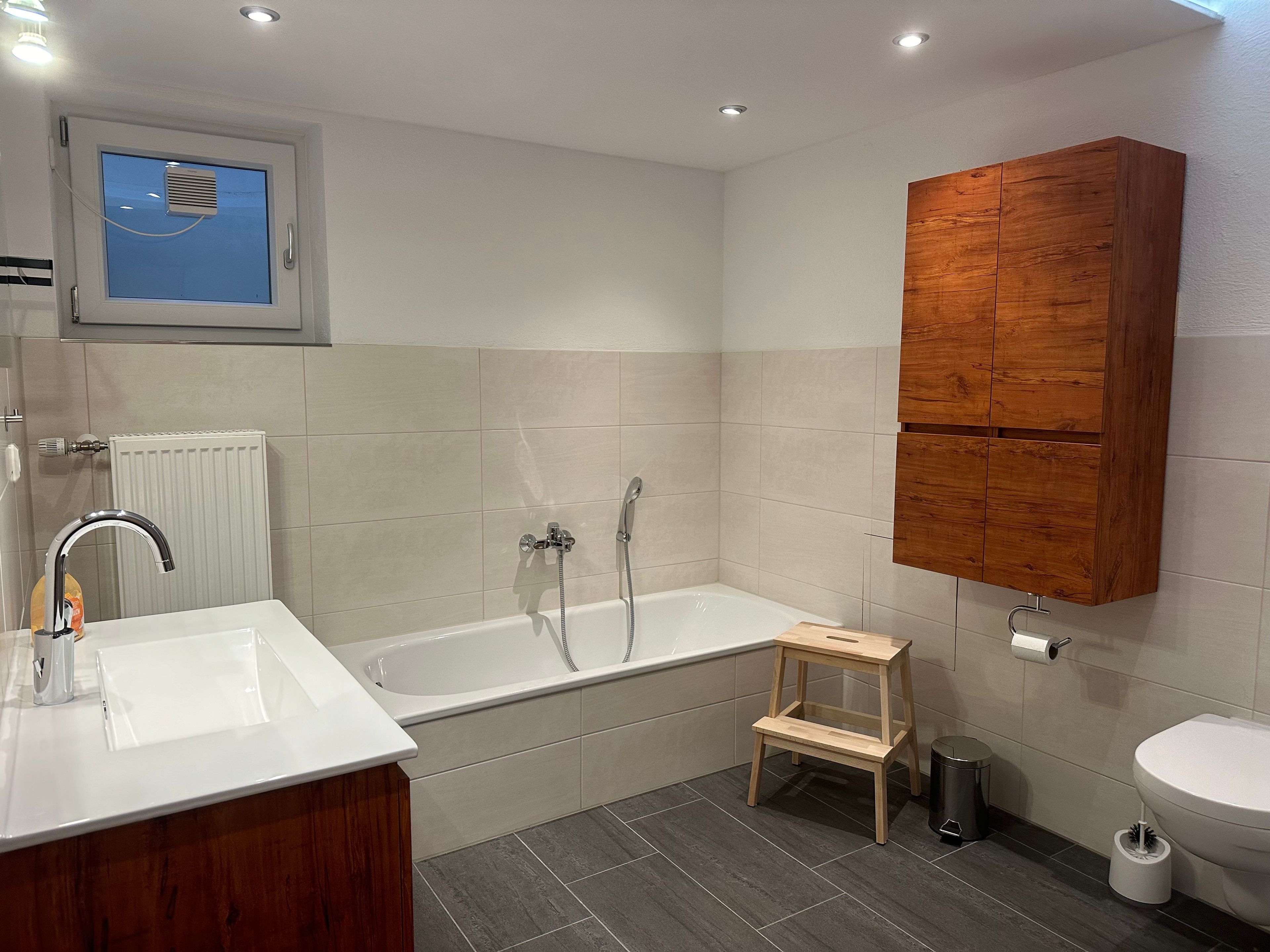 Une salle de bain moderne avec une baignoire, un lavabo, un meuble en bois et des toilettes.