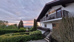 Un bâtiment à deux étages doté d’un balcon, entouré de verdure et offrant une vue panoramique.