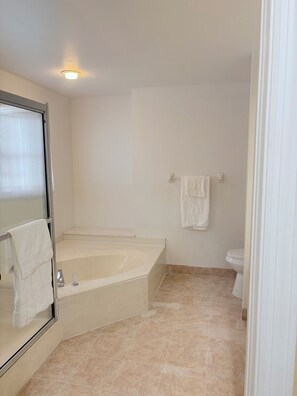 Ein Badezimmer mit Badewanne, Toilette und Duschbereich.