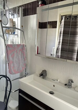 Ein Badezimmer mit einem weißen Waschbecken, einem Spiegel und einem Handtuchhalter.