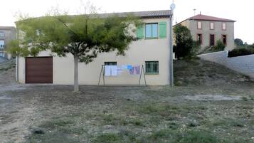 A building with a tree in front, a clothesline with laundry, and a satellite dish.