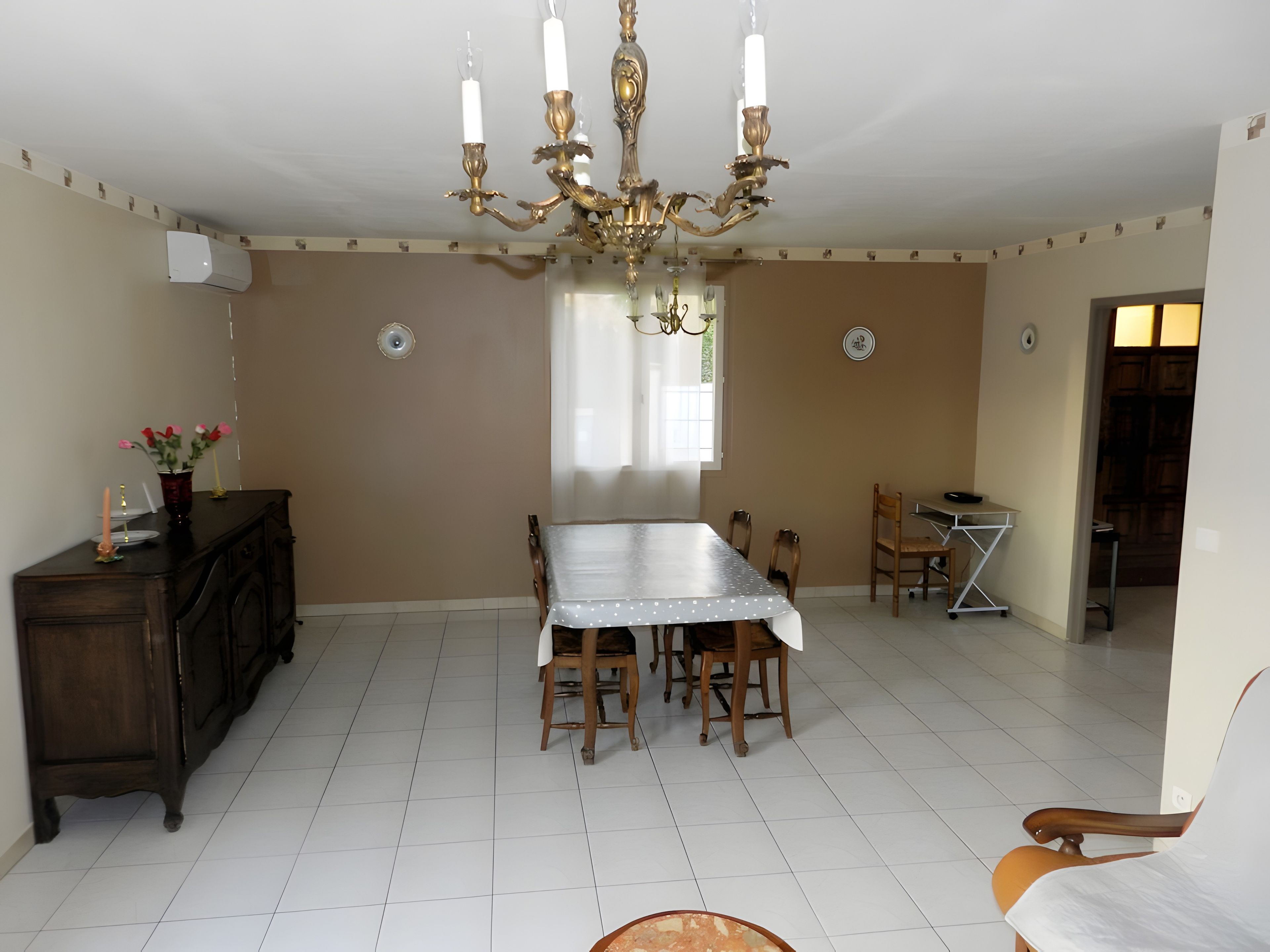 A dining area with a chandelier, a dining table, chairs, and a cabinet.