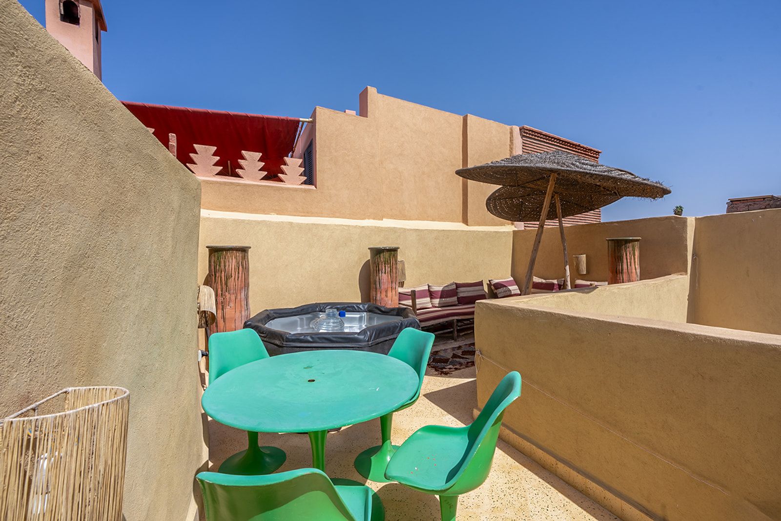 Un patio con una mesa, sillas, dispensador de agua y un muro decorado.