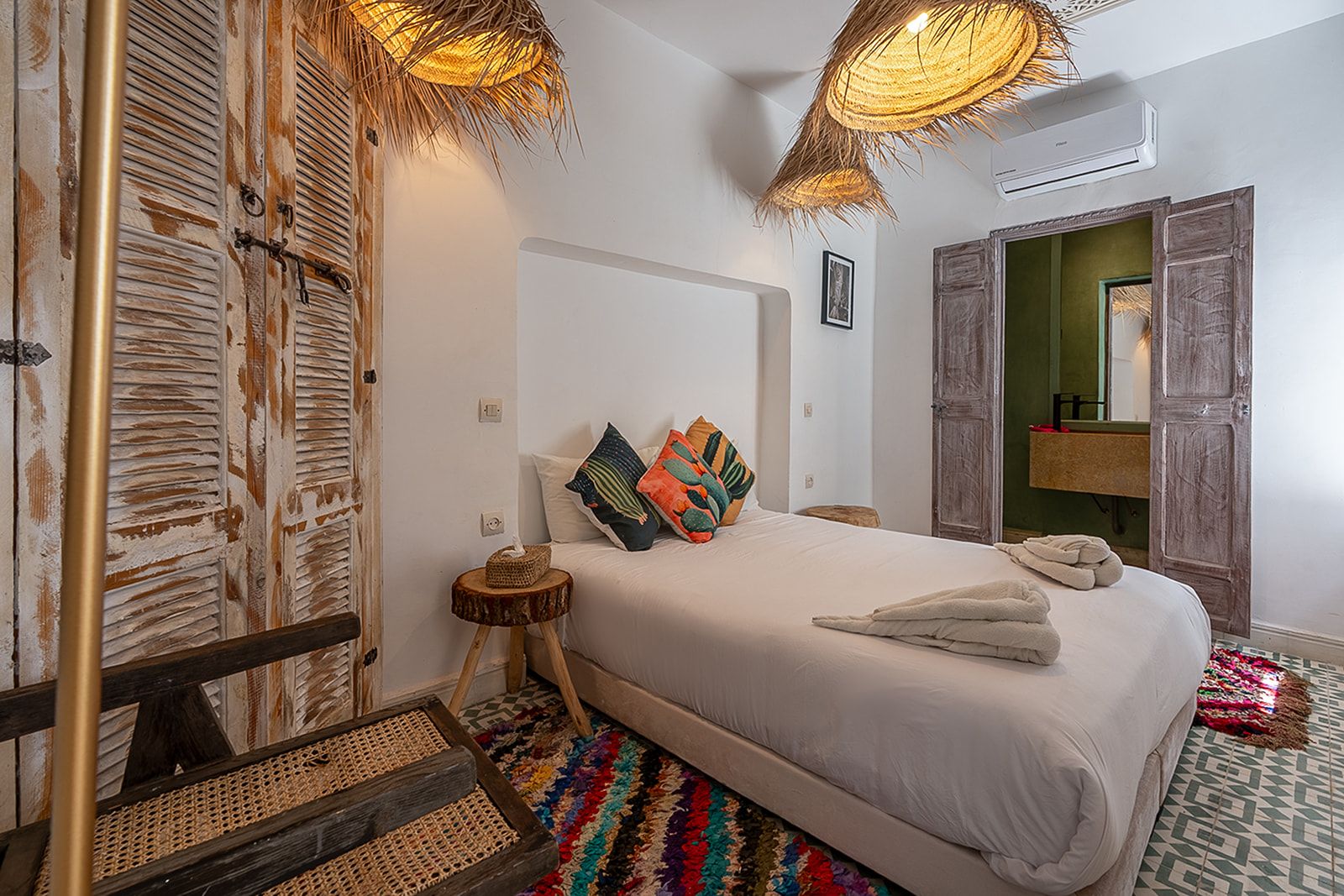 Un dormitorio con cama, mesita de noche, espejo y puerta.